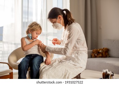 Niño pequeño, niño rubio, que se inyecta en consultorio desde pediatría, vacunación anual.