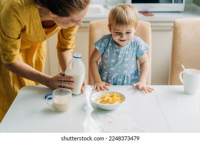 Little toddler daughter spilled milk on the table. - Shutterstock ID 2248373479