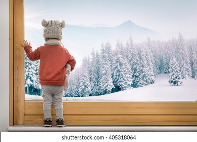 Little Toddler Girl Boy Looking Through Window At A Snowy Landscape Forest Winter Dreamy