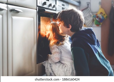 Little Toddler Girl And Two Kids Boys Baking, Pizza Or Cookies In Kitchen. Three Children, Siblings, Brothers And Sister Sitting Near Oven And Waiting. On Thanksgiving Or Christmas Holiday.