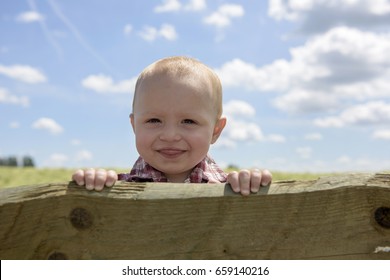 Little toddler  outdoors looking over a fence