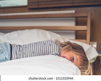A little toddler is relaxing on the bed in a city apartment