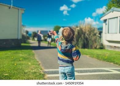 A Little Toddler Is Standing In A Trailer Park Waving At His Family