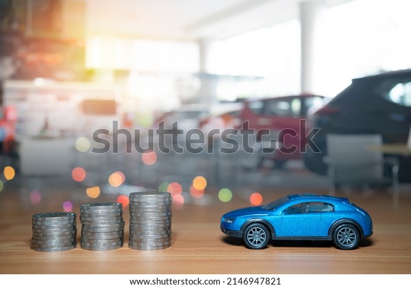 Little toy blue car\
over a lot of money stacked coins. for bank loans costs finance.\
insurance, buying car finance concept. buy and pay by installments\
down payment a car.