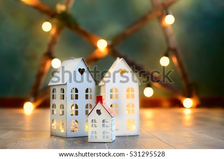 little toy Christmas houses with a burning light inside is on blurred green background. Real estate, holiday, xmas, miniature