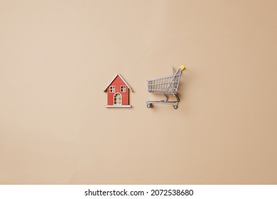 Little toy house and shopping cart on stark white background. Above view