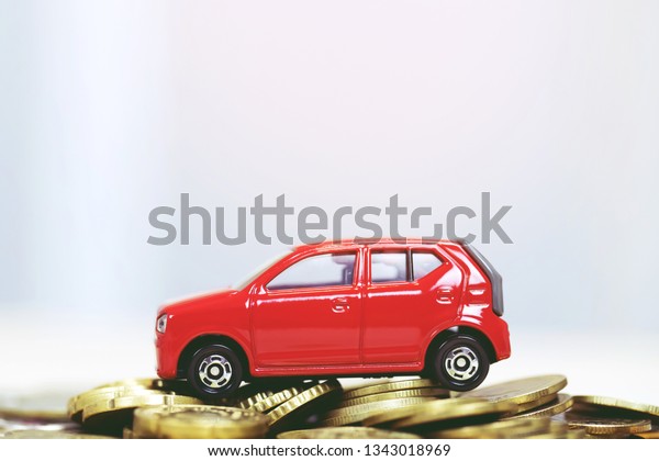 Little toy red car\
over a lot of money stacked coins. for  bank loans costs finance.\
insurance, buying car finance concept. buy and pay by installments\
down payment a car.