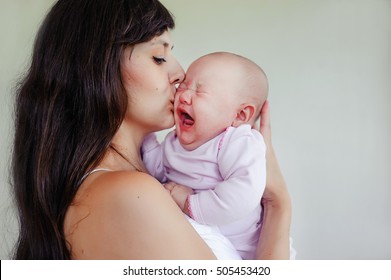 The Little Two-month Girl Cries At The Mother On Hands. Mother And Daughter. Children's Cry And Tears. Mom Comforts A Newborn Baby.