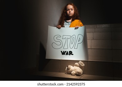 A Little Ukrainian Curly-haired Girl Sits In The Dark On The Stairs With A Poster Stop War. She Is From Odessa
