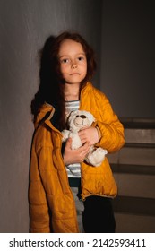 A Little Ukrainian, Sad, Curly-haired Girl Stands In The Dark On The Stairs With A Bear. She Is From Odessa
