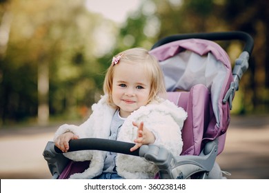 little  and very beautiful girl sitting in the pram and waiting for mom