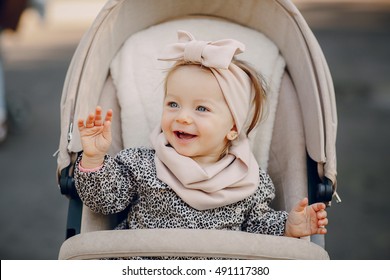 little  and very beautiful girl sitting in the pram and waiting for mom