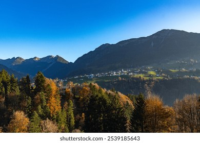 little village on green meadows on a terrace on steep slope from forested mountain. beautiful view with autumnal colored forests. amazing hiking area with slow tourism in Great Walser valley, holiday - Powered by Shutterstock