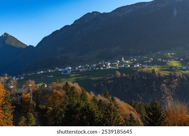 little village on green meadows on a terrace on steep slope from forested mountain. beautiful view with autumnal colored forests. amazing hiking area with slow tourism in Great Walser valley, holiday - Powered by Shutterstock