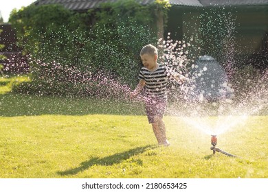 A little wet boy runs barefoot on the lawn next to the sprinkler. Happy carefree childhood and holidays concept.  - Powered by Shutterstock