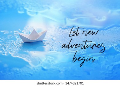little white paper boat on blue background. Let new adventures begin - inspiration quote. Travel concept. folded Origami paper boat on water. 