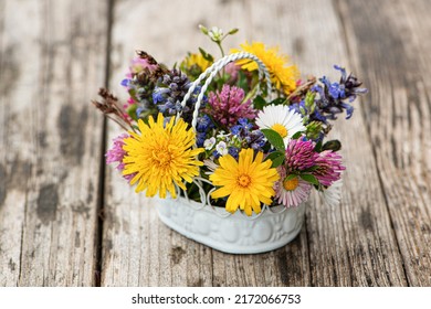 Little wild flower bouquet in a little basket on wooden table - Shutterstock ID 2172066753