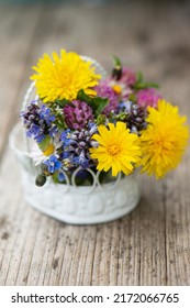 Little wild flower bouquet in a little basket on wooden table