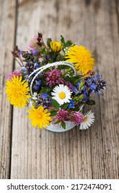 Little wild flower bouquet in a little basket on wooden table