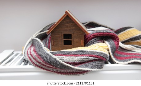 The little wooden house wrapped in the scarf lying on the radiator in the house