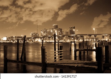 A little wooden old and rotten pier with the lights of the Miami city as a background.
