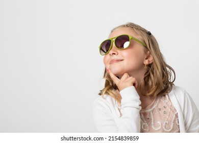 Little Young Teen Girl, Posing Mischievously In The Studio. The Background Is White And She Has Green Sunglasses That Are Really Too Big For Her.