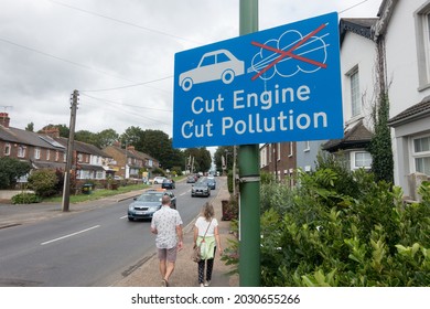 Littlehampton-UK-August 20,2021 : A Road Sign Says 'cut Engine Cut Pollution' .Car With Exhaust Fumes Crossed Out Are On The Sign.Traffic Passes By In A Residential Area With Houses And People Walking