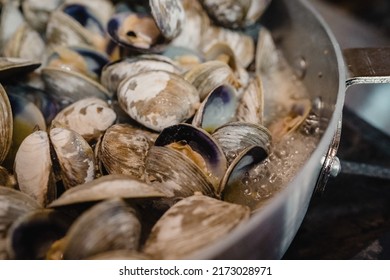 littleneck clams boiling in a pan on the stove