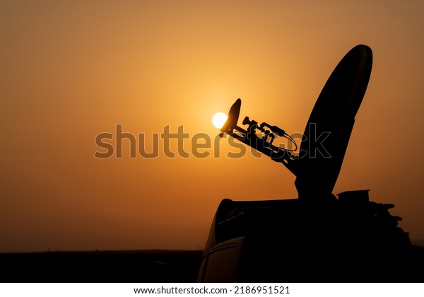 Live broadcast satellite antenna silhouette on an\
impressive summer sunset background. The dish satellite antenna is\
facing the sun.