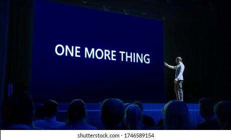 Live Event With Brand New Products Reveal: Keynote Speaker Presents New Device To Audience. Movie Theater Screen Shows Text -one More Thing-