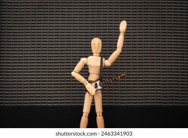 Live guitar music concept. Wooden mannequin playing an electric guitar with one arm raised in front of a guitar amp speaker. Rock music concert performance - Powered by Shutterstock