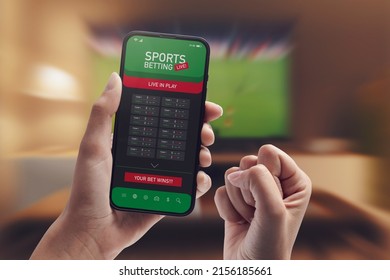 Live in-play betting app on smartphone display, a woman is betting at home and winning, POV shot - Shutterstock ID 2156185661