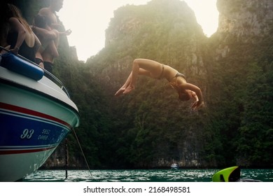 Live life with no regrets. Shot of a young woman doing a backflip off a boat while her friends watch. - Powered by Shutterstock