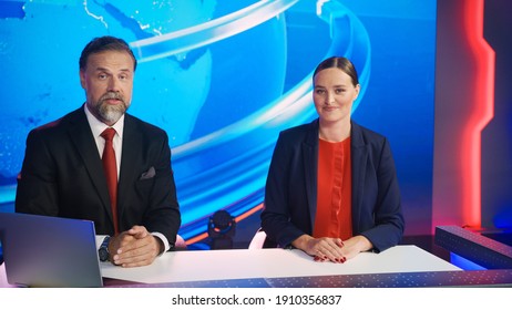 Live News Studio With Beautiful Female And Handsome Man Anchors Start Reporting. TV Broadcasting Channel With Presenters Talking. Inside Mock-up Television Newsroom Set.