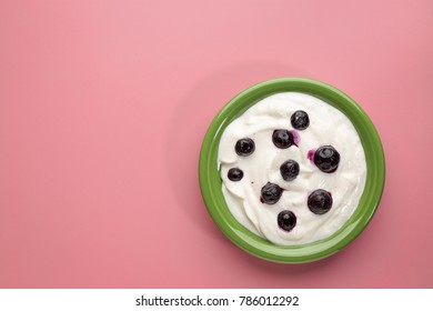 Live Organic Greek Yogurt With Vanilla And Blueberries In A Green Ceramic Bowl Against Pink Background