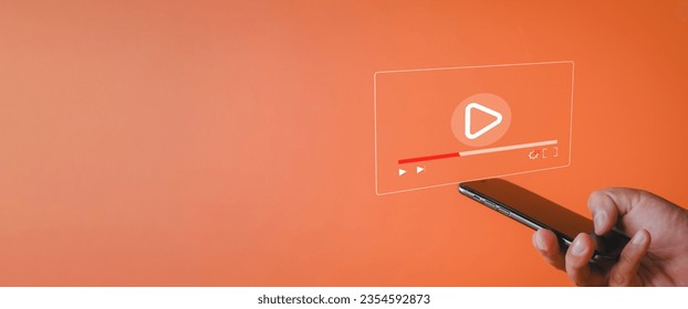 Live stream,Online live video,Online Marketing,e-learning,education,training,social media concept.,Hand holding smartphone with Multimedia video player icon over orange background with copyspace.