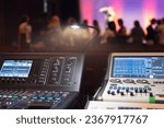 Live theater concert show sound video music control console with scene lights background. Sound engineer mixer soundboard equipment with many knobs, buttons, faders, equalizer screen and light