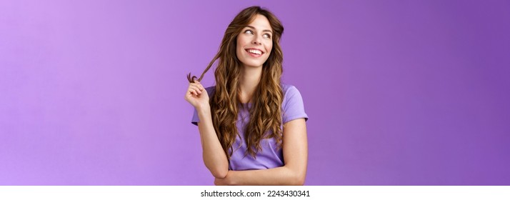 Lively arrogant good-looking girl curly stylish haircut look away dreamy delighted daydreaming thoughtful gaze away touch hair strand rolling curly smiling broadly stand purple background. Lifestyle.