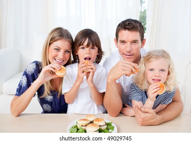 Lively Family Eating Burgers In The Living Room At Home