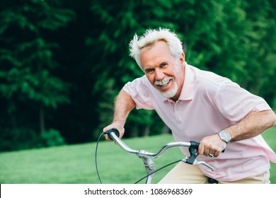 Lively Older Man Riding His Bicycle, Laughs And Enjoys Life. Senior Man On Bike, Having Fun