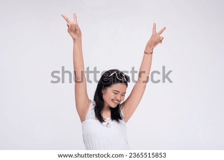 A lively party girl raising her arms in glee making victory signs. Isolated on a white background.
