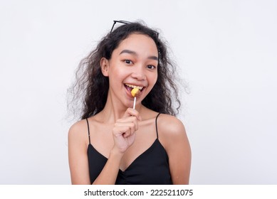 A lively and perky asian woman holding a lollipop. Isolated on a white background. - Shutterstock ID 2225211075