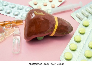 Liver treatment concept photo. Figure liver surrounded by pills, medications, medicine vials with syringe, symbolizing treatment, prevention and protection of liver from bacteria, viruses and toxins