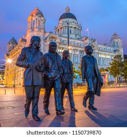 LIVERPOOL, UK - JULY 29TH 2018: Statues of The Beatles - Paul, George, Ringo and John on Pier Head in Liverpool, UK, with the Port of Liverpool building in the background, on 29th July 2018.