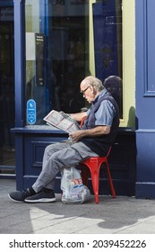 Liverpool, United Kingdom, 09.06.2021:  An Older Man Reading A Paper Outside Of A Shop.