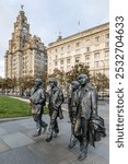 Liverpool waterfront, the Beatles statues and the Liver Building. Iconic Liverpool band from the UK. Swinging Sixties music statues.