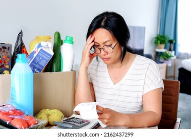 Living cost inflation crisis high cost in gas electric energy woman holding receipts from supermarket with calculator by rising grocery prices and surging cost as an inflation financial crisis. - Shutterstock ID 2162437299