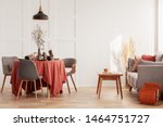 Living and dining room interior with grey couch and table covered with orange tablecloth