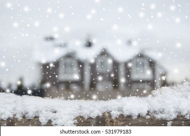 Living Place In Winter, Snowfall. December. Defocused Country House With Car And Fence In Snow. Wooden Plank In Snow In Front Side.