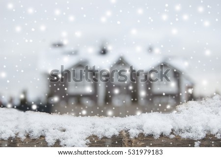 Living place in winter, snowfall. December. Defocused country house with car and fence in snow. Wooden plank in snow in front side.